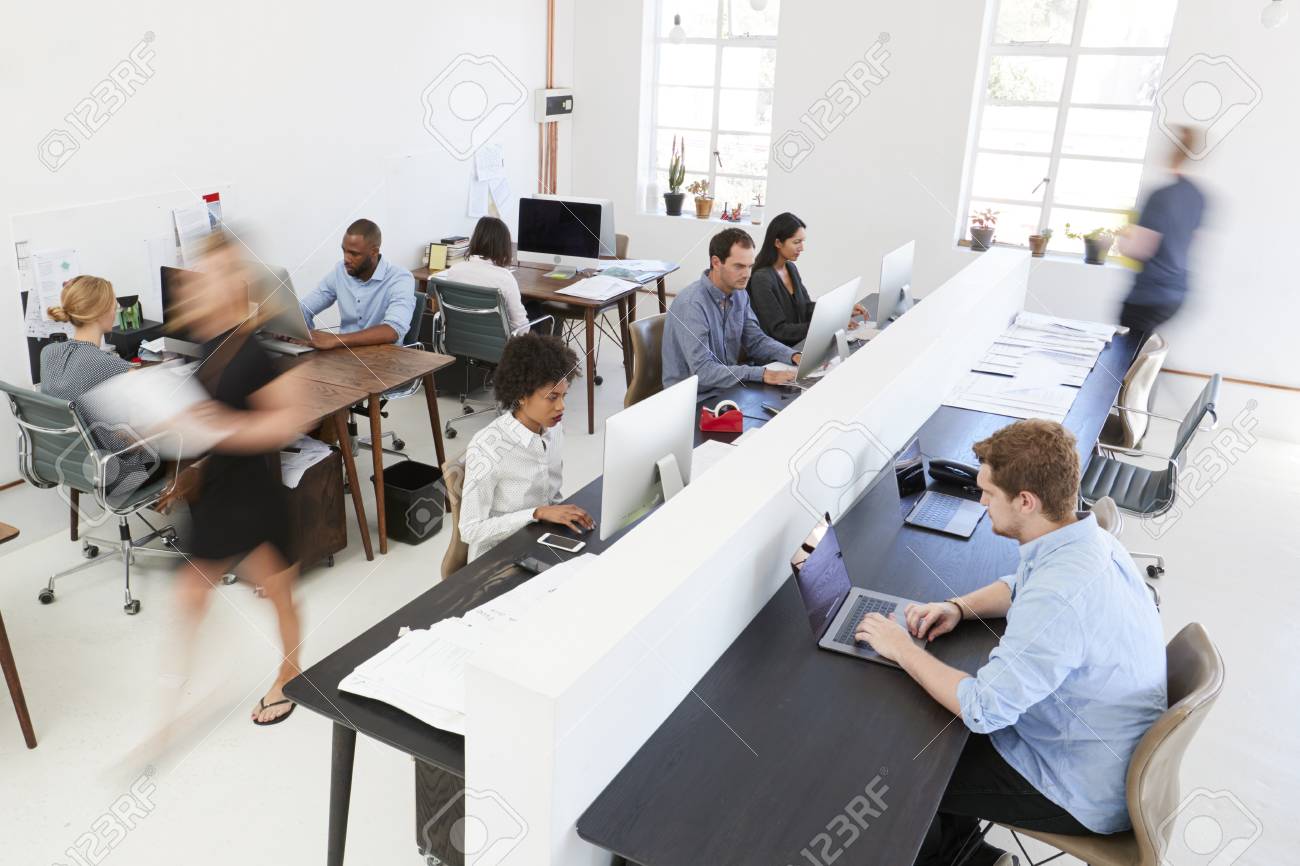 Young colleagues at computers in a busy open plan office
